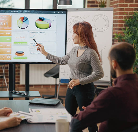 Asian woman explaining creative ideas to business people, meeting to work on presentation development. Colleagues discussing company growth with data graphics on monitor. Partnership