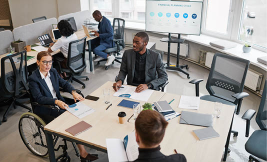 Portrait of smiling businesswoman using wheelchair while speaking at business meeting in office, copy space
