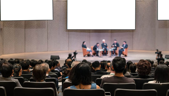 Rear view of Audience over the speakers on the stage in the conference hall or seminar meeting, business and education concept